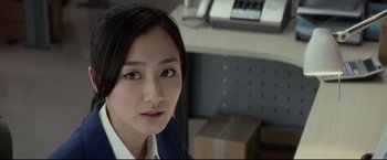 Movie still from “Man of Tai Chi” (2013), directed by Keanu Reeves – A woman in a suit sitting in front of a computer desk; Close Up shot, Over the shoulder angle