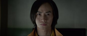 Movie still from “Man of Tai Chi” (2013), directed by Keanu Reeves – A person with long black hair; Close Up shot, Low angle