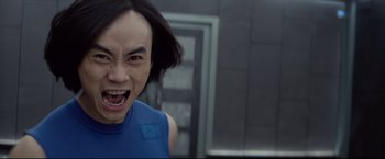 Movie still from “Man of Tai Chi” (2013), directed by Keanu Reeves – A person with a blue shirt and black hair; Close Up shot, Low angle