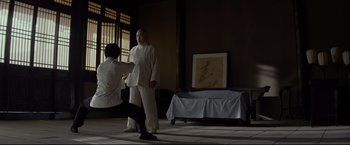 Movie still from “Man of Tai Chi” (2013), directed by Keanu Reeves – A man and a woman are practicing martial arts in a room; Wide shot, Low angle