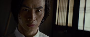 Movie still from “Man of Tai Chi” (2013), directed by Keanu Reeves – A person with long black hair; Close Up shot, Low angle