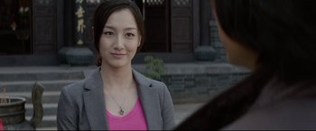 Movie still from “Man of Tai Chi” (2013), directed by Keanu Reeves – A woman in a pink shirt and a gray suit jacket; Close Up shot, Over the shoulder angle