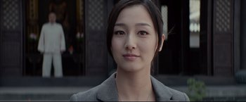 Movie still from “Man of Tai Chi” (2013), directed by Keanu Reeves – A young woman with long black hair wearing a gray suit; Close Up shot, Low angle