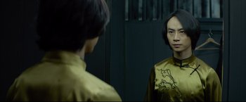 Movie still from “Man of Tai Chi” (2013), directed by Keanu Reeves – A woman in a yellow shirt looking at her reflection in a mirror; Close Up shot, Over the shoulder angle