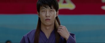 Movie still from “Man of Tai Chi” (2013), directed by Keanu Reeves – A young man with long hair is wearing a purple robe; Close Up shot, Low angle