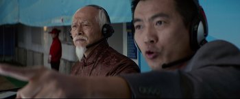 Movie still from “Man of Tai Chi” (2013), directed by Keanu Reeves – Two men wearing headsets and one of them has a beard; Close Up shot, Over the shoulder angle