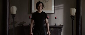 Movie still from “Man of Tai Chi” (2013), directed by Keanu Reeves – A man standing in front of a painting and candles; Medium shot, Low angle