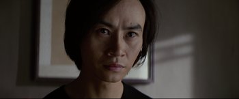 Movie still from “Man of Tai Chi” (2013), directed by Keanu Reeves – A person's face in front of a window; Close Up shot, Low angle