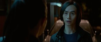 Movie still from “Man of Tai Chi” (2013), directed by Keanu Reeves – A man standing next to another man in a room; Close Up shot, Over the shoulder angle