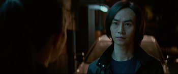 Movie still from “Man of Tai Chi” (2013), directed by Keanu Reeves – A man standing in front of a car on a street; Close Up shot, Over the shoulder angle