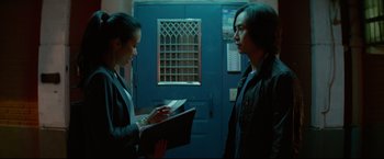 Movie still from “Man of Tai Chi” (2013), directed by Keanu Reeves – Two people standing next to each other in front of a blue door; Medium shot, Over the shoulder angle