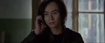 Movie still from “Man of Tai Chi” (2013), directed by Keanu Reeves – A man holding a cell phone up to his ear; Close Up shot, High angle