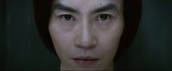 Movie still from “Man of Tai Chi” (2013), directed by Keanu Reeves – A man's face with a dark background; Extreme Close Up shot, Low angle