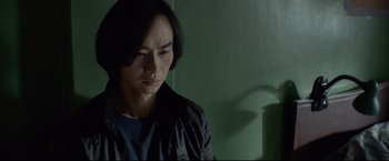 Movie still from “Man of Tai Chi” (2013), directed by Keanu Reeves – A man in a black jacket is looking at the camera; Close Up shot, High angle