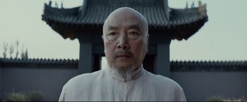 Movie still from “Man of Tai Chi” (2013), directed by Keanu Reeves – An older man wearing a white shirt and a white hat; Close Up shot, Low angle