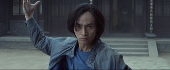Movie still from “Man of Tai Chi” (2013), directed by Keanu Reeves – A man with long black hair wearing a blue shirt; Close Up shot, Low angle