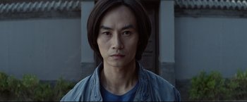 Movie still from “Man of Tai Chi” (2013), directed by Keanu Reeves – A person wearing a blue shirt; Close Up shot, Low angle