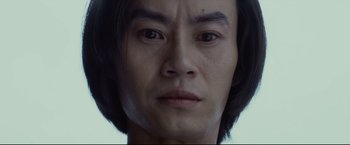 Movie still from “Man of Tai Chi” (2013), directed by Keanu Reeves – A man's face with a black wig; Extreme Close Up shot, Low angle