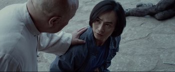 Movie still from “Man of Tai Chi” (2013), directed by Keanu Reeves – An older man touching the shoulder of an older man; Close Up shot, Over the shoulder angle