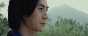 Movie still from “Man of Tai Chi” (2013), directed by Keanu Reeves – A man's face with trees in the background; Close Up shot, Low angle