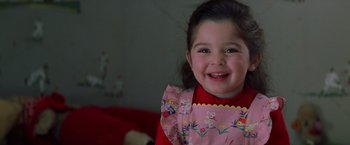 Movie still from “Man on the Moon” (1999), directed by Milos Forman – A little girl smiling for the camera with a teddy bear in the background; Close Up shot, High angle