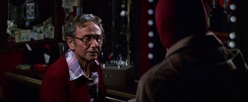 Movie still from “Man on the Moon” (1999), directed by Milos Forman – An older man wearing glasses and a red jacket; Close Up shot, Over the shoulder angle