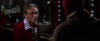 Movie still from “Man on the Moon” (1999), directed by Milos Forman – An older man wearing glasses and a red jacket; Close Up shot, Over the shoulder angle