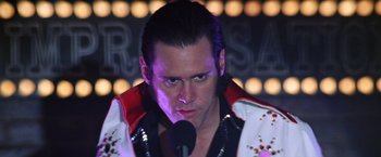 Movie still from “Man on the Moon” (1999), directed by Milos Forman – A man with a microphone in front of lights; Close Up shot, Low angle