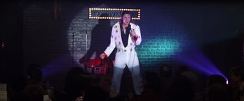 Movie still from “Man on the Moon” (1999), directed by Milos Forman – A man dressed as elvis presley on a stage; Wide shot, Low angle