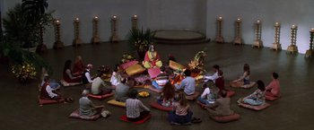 Movie still from “Man on the Moon” (1999), directed by Milos Forman – A group of people sitting on the ground in front of a statue; Wide shot, High angle