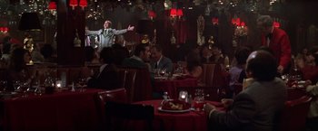 Movie still from “Man on the Moon” (1999), directed by Milos Forman – A group of people sitting at tables in a restaurant; Wide shot, Over the shoulder angle