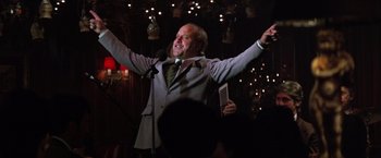 Movie still from “Man on the Moon” (1999), directed by Milos Forman – A man in a suit and tie holding a microphone; Medium shot, Low angle