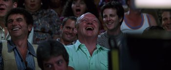 Movie still from “Man on the Moon” (1999), directed by Milos Forman – An older man is laughing while sitting in the audience; Close Up shot, Over the shoulder angle