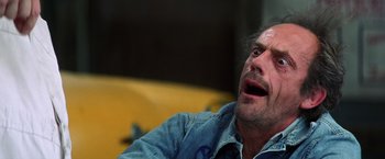 Movie still from “Man on the Moon” (1999), directed by Milos Forman – A person sitting on a couch with his mouth wide open; Close Up shot, Low angle