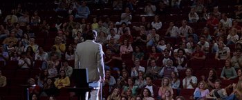 Movie still from “Man on the Moon” (1999), directed by Milos Forman – A man standing in front of an audience in front of a microphone; Extreme Wide shot, High angle