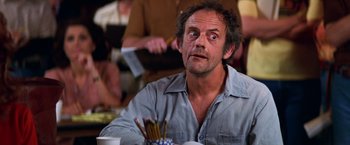 Movie still from “Man on the Moon” (1999), directed by Milos Forman – A man sitting in front of a table with pencils; Close Up shot, Over the shoulder angle