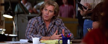 Movie still from “Man on the Moon” (1999), directed by Milos Forman – A man sitting at a table in front of a bunch of papers; Close Up shot, Over the shoulder angle