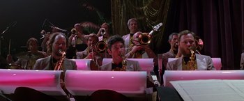 Movie still from “Man on the Moon” (1999), directed by Milos Forman – A group of people playing musical instruments in a room; Wide shot, Low angle