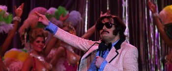 Movie still from “Man on the Moon” (1999), directed by Milos Forman – A man dressed as elvis in a pink and white suit; Medium shot, Low angle