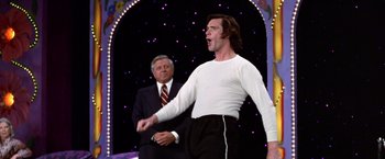 Movie still from “Man on the Moon” (1999), directed by Milos Forman – A man in a white shirt and black pants standing next to a man in a white shirt; Medium shot, Low angle