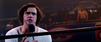 Movie still from “Man on the Moon” (1999), directed by Milos Forman – A man holding a microphone in front of a mirror; Close Up shot, Over the shoulder angle