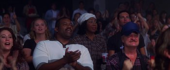 Movie still from “Man on the Moon” (1999), directed by Milos Forman – A group of people sitting in front of a crowd; Medium shot, Over the shoulder angle