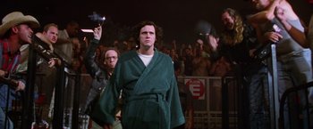 Movie still from “Man on the Moon” (1999), directed by Milos Forman – A man in a robe is standing in front of a group of onlookers; Medium shot, Low angle