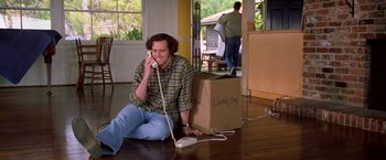 Movie still from “Man on the Moon” (1999), directed by Milos Forman – A man sitting on the floor talking on a phone; Wide shot, High angle