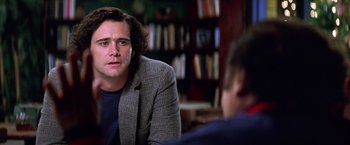 Movie still from “Man on the Moon” (1999), directed by Milos Forman – A man sitting in front of another man in front of bookshelves; Close Up shot, Over the shoulder angle