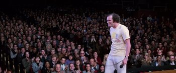 Movie still from “Man on the Moon” (1999), directed by Milos Forman – A crowd of people watching a man on a stage; Wide shot, Over the shoulder angle