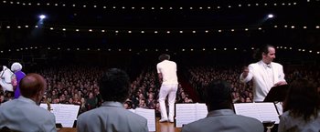 Movie still from “Man on the Moon” (1999), directed by Milos Forman – A man standing on a stage in front of an audience; Wide shot, Low angle