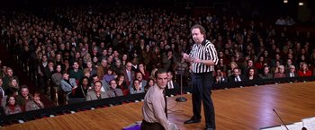 Movie still from “Man on the Moon” (1999), directed by Milos Forman – Two men in front of a crowd of people in front of an audience; Wide shot, High angle