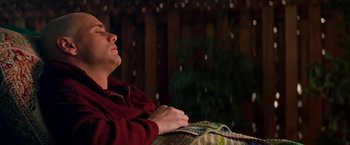 Movie still from “Man on the Moon” (1999), directed by Milos Forman – A man sitting on top of a couch in a living room; Medium shot, High angle