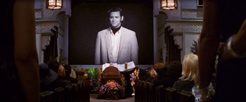 Movie still from “Man on the Moon” (1999), directed by Milos Forman – A picture of a man on a large screen in front of a crowd; Wide shot, Over the shoulder angle